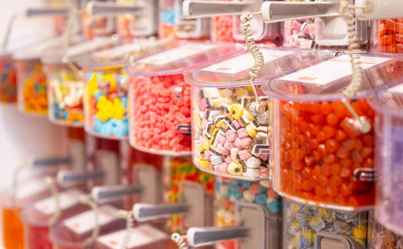 Rows of clear plastic bins filled with assorted colorful candies in a self‑serve display.