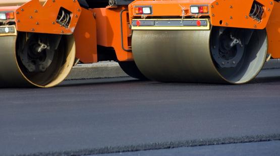 Road construction equipment rolls newly paved road