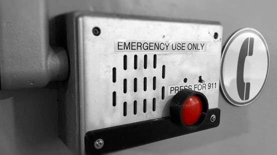 Airport emergency intercom with speaker, red 911 button, and signage.