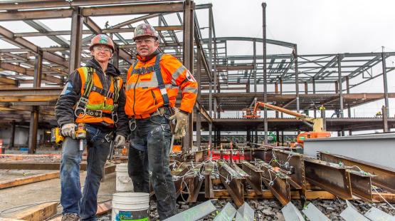 Construction workers standing with tools in front of the beams on a 2 or 3 story building