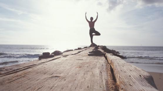 Woman doing yoga at the end of a pier.