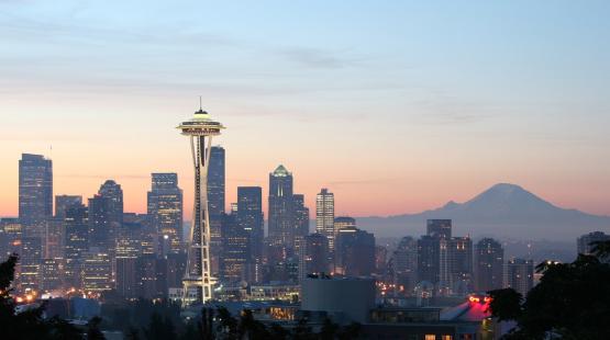 Seattle skyline at sunset with Mount Rainier in the background and Space Needle in the foreground. 