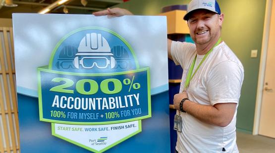 Wireman Foreman Chris Todd stands next to a poster promoting the Port's commitment to 200% accountability