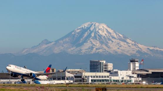 Delta airlines jet takes off from SEA Airport in front of Mt. Rainier.