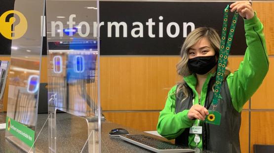 Pathfinder holds up a sunflower lanyard at the SEA information desk.