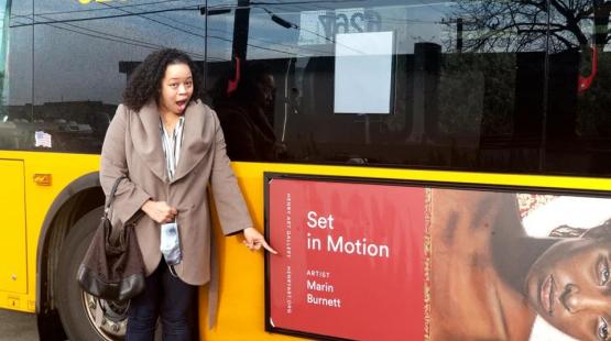 Marin Burnett standing in front of a bus with her artwork on it.