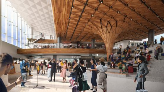 A spacious airport interior with a patterned wooden ceiling, multiple levels of shops and walkways, and travelers gathered near a musician in the open central area.