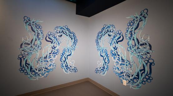 Two mirrored wall installations of flowing blue serpentine forms installed in a corner of the SEA Airport.