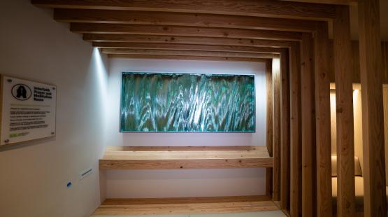 A backlit panel mounted in a wood-framed alcove inside SEA Airport Interfaith Prayer and Meditation room. 
