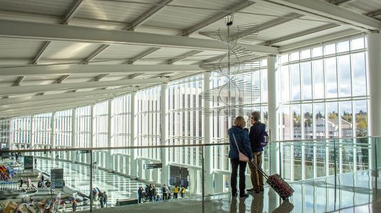 Two people with luggage stand overlooking the Grand Hall at the IAF 