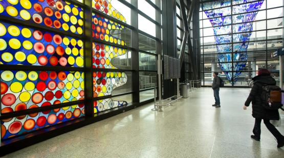 Cow on its Side by Dick Weiss:  A stained-glass window mosaic of circular rondelles set against wavy lines with a rippling, humped silhouette along the right edge. 