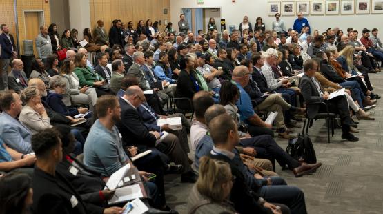 A large audience seated in a conference room during a presentation.