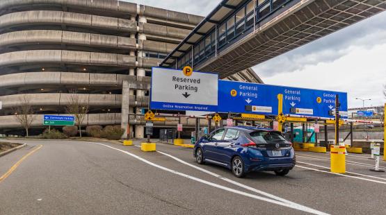 A blue car entering the SEA airport parking garage.