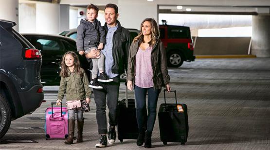 A family walks through the SEA parking garage with luggage.