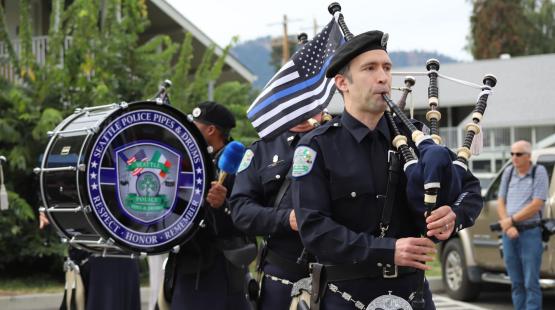 Officer playing the bagpipes, a drummer in the background.