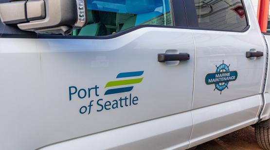 Side view of a white truck displaying the Port of Seattle logo and a Marine Maintenance emblem on the doors.