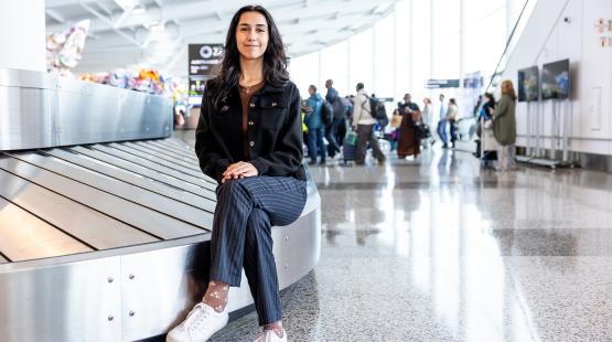 Cilicia Diaz sits by the bag carousel in the International Arrivals Facility.