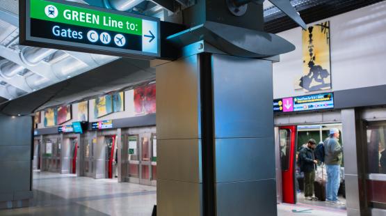 Overhead airport sign with a green header reading ‘GREEN Line to:’ and directional symbols pointing right toward Gates C, N, and X.