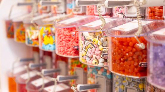 Rows of clear plastic bins filled with assorted colorful candies in a self‑serve display.